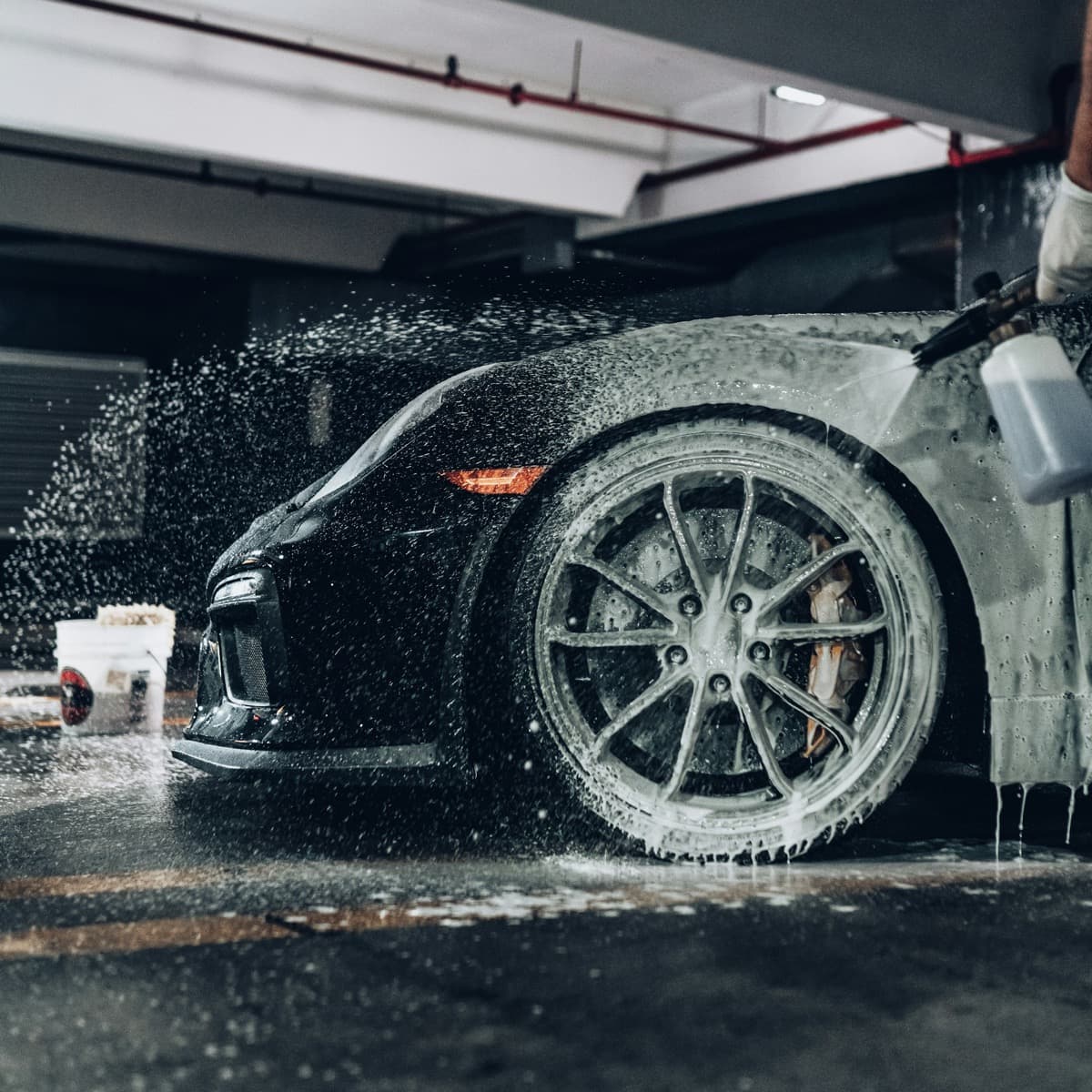 Roda mobil berbusa disemprot di dalam bengkel carwash