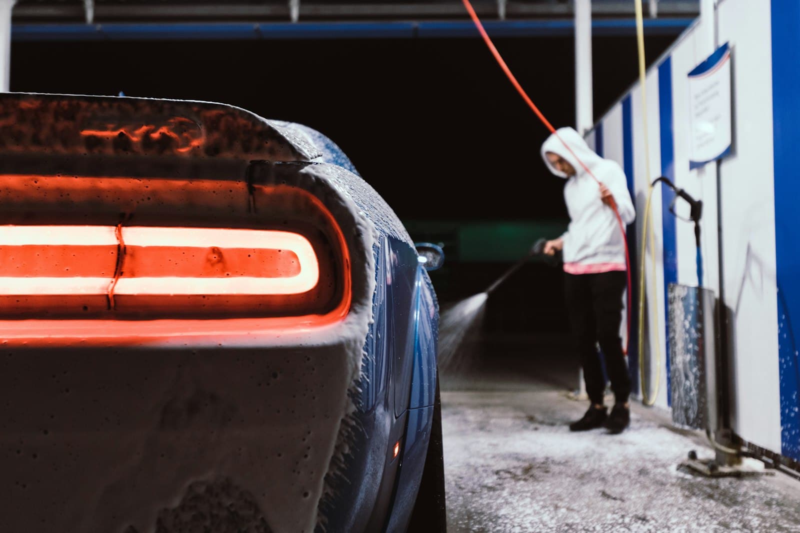 Petugas menyemprot mobil dengan air bertekanan pada malam hari